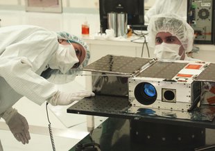 Electrical Test Engineer Esha Murty and Integration and Test Lead Cody Colley prepare the ASTERIA spacecraft for mass-properties measurements in April 2017. ASTERIA was deployed from the International Space Station in November 2017.