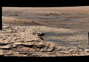 NASA's Curiosity Mars rover captured this view from "Greenheugh Pediment" on April 9, 2020. In the foreground is the pediment's sandstone cap. At center is the "clay-bearing unit"; the floor of Gale Crater is in the distance.