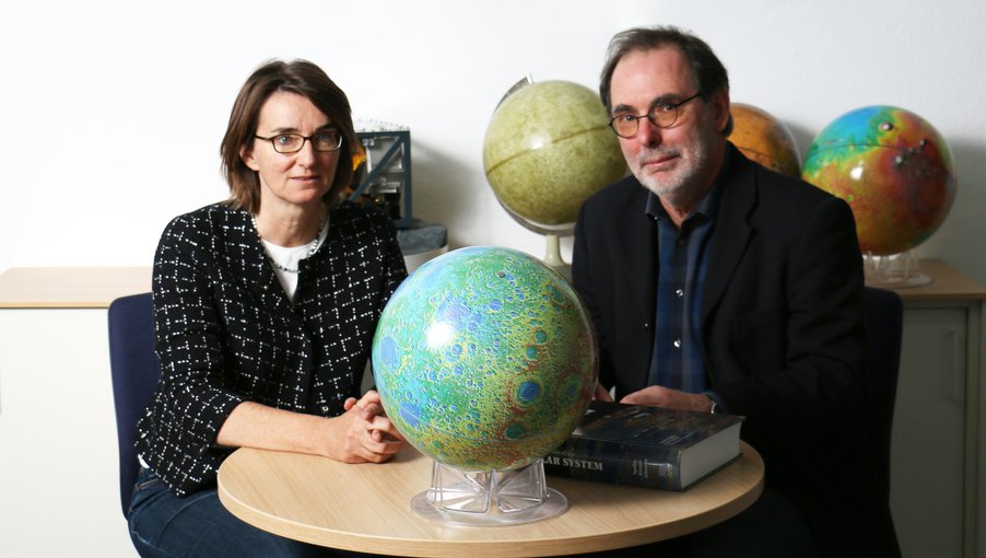 Rauer and Spohn sit at a either end of a table with a globe of Earth between them.