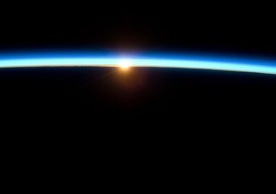 The thin line of Earth's atmosphere and the setting sun are featured in this image photographed by the crew of the International Space Station while space shuttle Atlantis on the STS-129 mission was docked with the station.