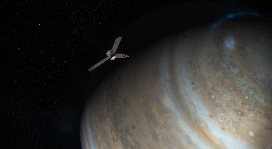 Artist concept shows spinning, solar powered Juno spacecraft in orbit above Jupiter's north pole. The bluish glow of the planet's auroras is seen far below.