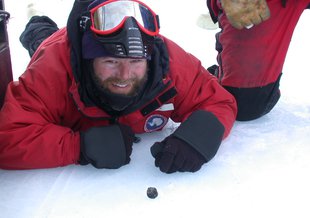 NASA Goddard astrobiologist Daniel Glavin poses in 2002 next to a meteorite he had just found during an expedition in Antarctica.