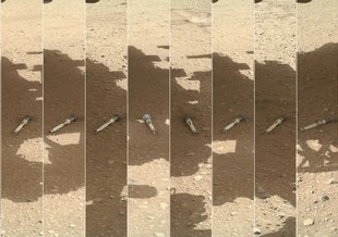 Ten small portrait images of sample tubes laying on the martian surface are combined to form one large landscape image. In each image a small tube sits on the ground in the shadow of the Perseverance rover. Perseverance (not visible) captured the images.
