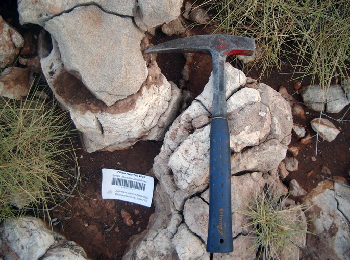 Serpentinized talc-carbonate komatiite rock from the Mount Ada Basalt in Australia's Pilbara region (hammer is for scale).