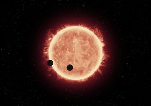 Artist’s illustration of two Earth-sized planets, TRAPPIST-1b and TRAPPIST-1c, passing in front of their parent red dwarf star, which is smaller and cooler than our sun. NASA’s Hubble Space Telescope looked for signs of atmospheres around these planets.
