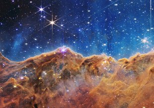 This landscape of “mountains” and “valleys” speckled with glittering stars is actually the edge of a nearby, young, star-forming region called NGC 3324 in the Carina Nebula. Captured in infrared light by NASA’s Webb Space Telescope.