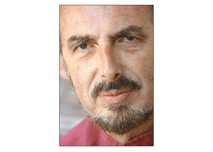 A very close shot of Pohorille's face. He has a goatee and mustache and wears a salmon pink collared shirt. The image is cropped below his hairline.