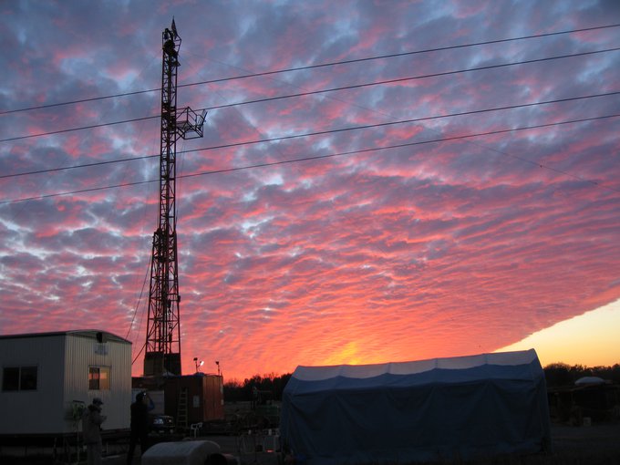The tower of the drilling rig for the Chesapeake Bay Impact Structure (CBIS) drilling project is seen against a vibrant sunset.