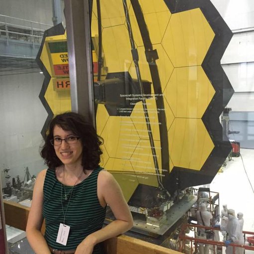 Giada Arney, research scientist at the Goddard Space Flight Center is an active member of the NASA NExSS program. Behind her is part of the mirror for the James Webb Space Telescope.