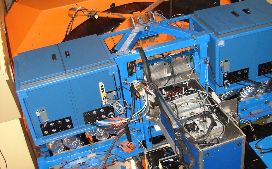 The HIPWAC instrument (protruding metal box) bolts to the back of the IRTF primary mirror, along with the supporting electronics and other instruments.