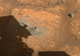 This image taken by one the hazard cameras aboard NASA’s Perseverance rover on Aug. 6, 2021, shows the hole drilled in what the rover’s science team calls a “paver rock” in preparation for the mission’s first attempt to collect a sample from Mars.