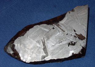 This 15cm wide fragment of the Seymchan meteorite found in Russia in 1967 is an iron-nickel pallasite. The long filament of dark grey material in the center is schreibersite.