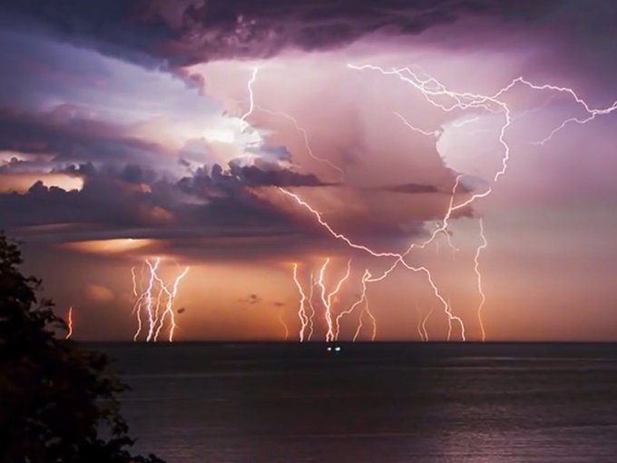 Video screen capture of long-exposure photo of lightning strikes over water.