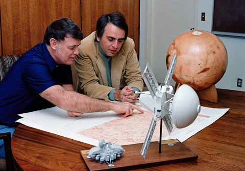 Bruce Murray (left), former Director of NASA's Jet Propulsion Laboratory, and Carl Sagan (right) look at a map of Mars. The picture was taken in 1976 in Murray's office while Sagan was living in Pasadena and working on NASA's Viking mission.