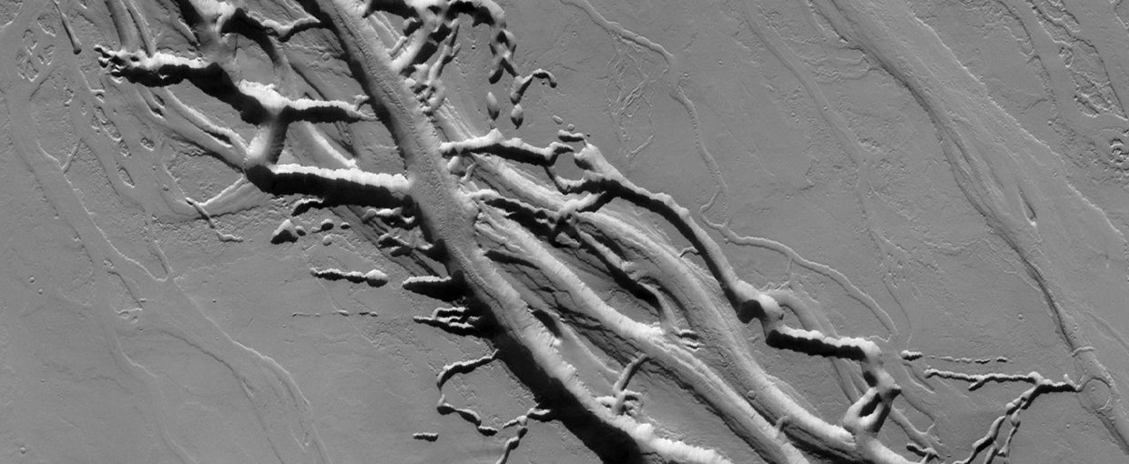 Located on the lava plains between Olympus Mons and Alba Mons, this image from NASA 2001 Mars Odyssey spacecraft shows complex intersecting valleys, which were created by lava flow. Volcanic flows occurred both along the surface and in buried lava tubes.