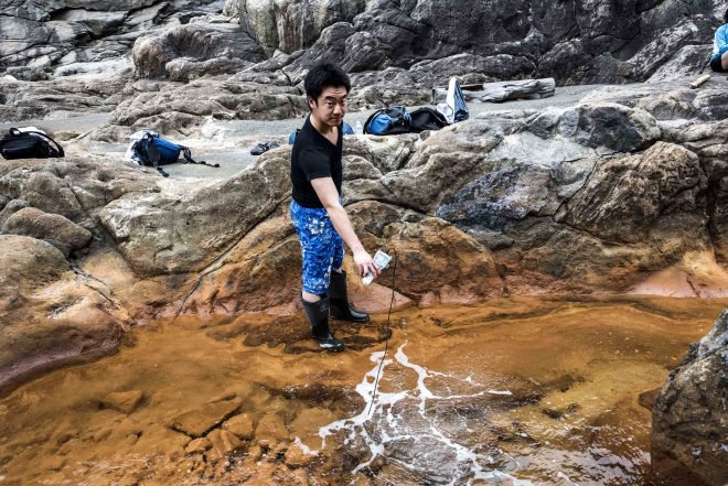 Tomohiro Mochizuki at collecting samples directly from the spot where 160 degree F water pushes up through the rock at Jinata hot spring.