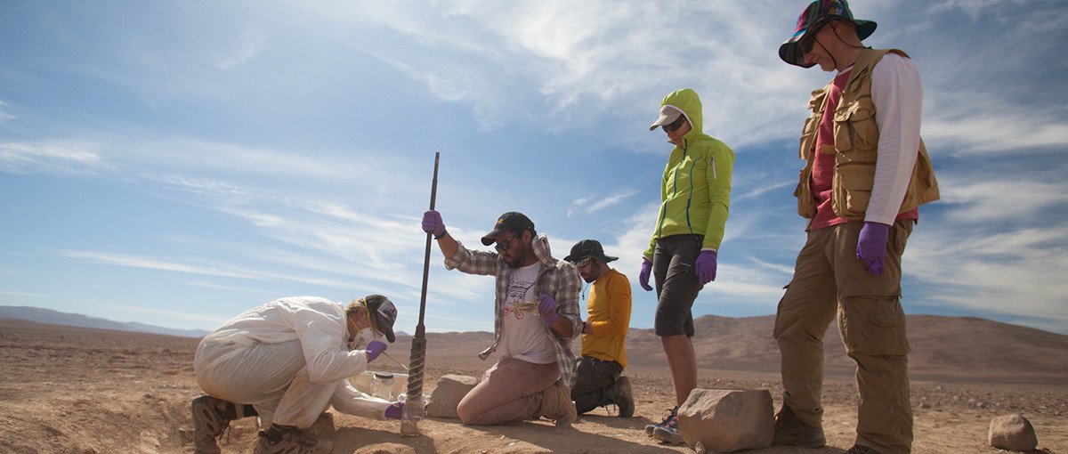 Mary Beth Wilhelm of NASA Ames Research Center, wearing the white suit, tests samples obtained from an excavation pit in Chile’s Atacama Desert. On the right are Miriam Villadangos and Victor Parro of the Centro de Astrobiología.