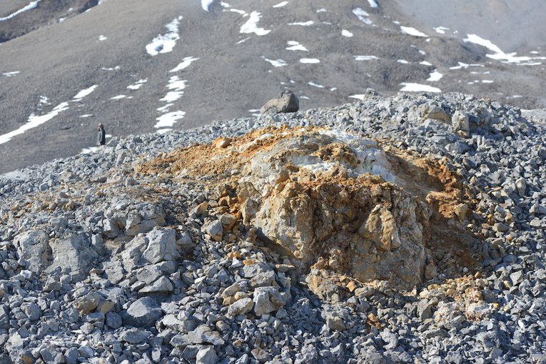 A gypsum paleopipe emerges out of a moraine of glacial talus on the south side of Borup Fiord Pass glacier.  The paleopipes are distinct for their gypsum and variable mineral coloring amidst the talus.