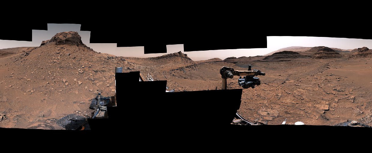 Panoramic view of the rust-colored martian surface from Curiosity. The sky is a hazy pink.