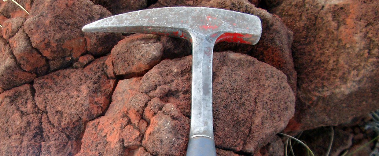 Serpentinized komatiite rock (right) from the Mount Ada Basalt in Australia's Pilbara region (hammer shown for scale).